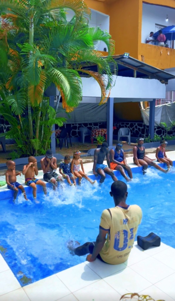 Groupe d'enfants en exercice de battements de jambes au bord du bassin